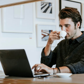 Man sipping coffee in front of laptop