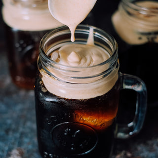 Adding cream to Pumpkin Cream Cold Brew in mason jar